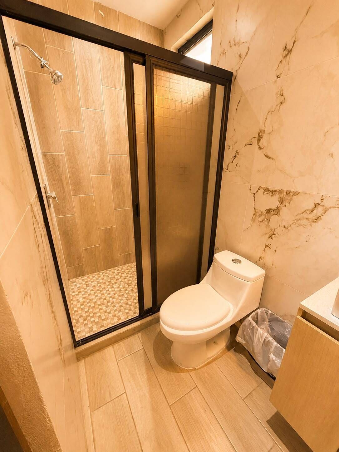 A bathroom with a shower enclosure, toilet, and a sink area.