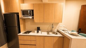 A compact kitchen with a built-in microwave, a coffee maker, and a sink.