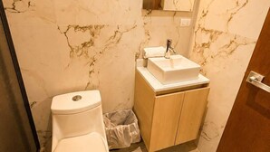A bathroom with a toilet, sink, mirror, and marble walls.