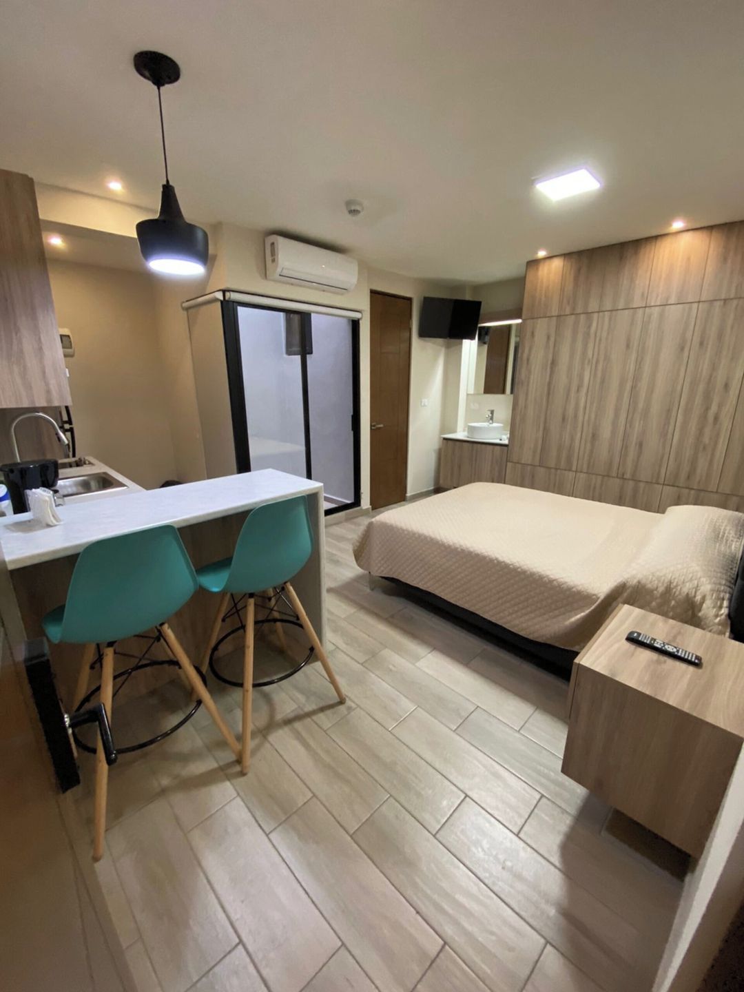 A hotel room with a bed, a desk with chairs, a TV, and a wardrobe.