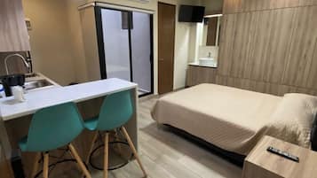 A hotel room with a bed, a desk with chairs, a TV, and a wardrobe.