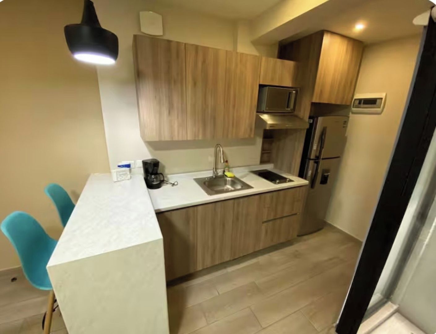 A compact kitchen with wooden cabinets, a stainless steel sink, and a microwave.