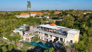 Un hotel moderno con piscina, varias edificaciones y una torre distintiva al fondo.
