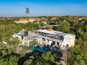 A modern hotel with a swimming pool, multiple buildings, and a distinctive tower in the background.