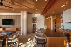 A modern kitchen with wooden cabinetry, a central island, and a built-in TV.