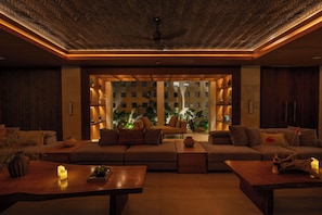 A modern living room with a large sofa, a coffee table, and a ceiling fan.