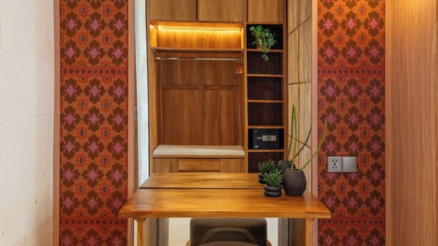 Una habitación pequeña con una mesa de madera, un banco y estanterías empotradas.