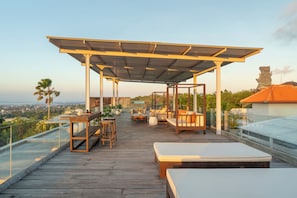 A rooftop terrace with a wooden deck, outdoor seating, and a view of the cityscape.