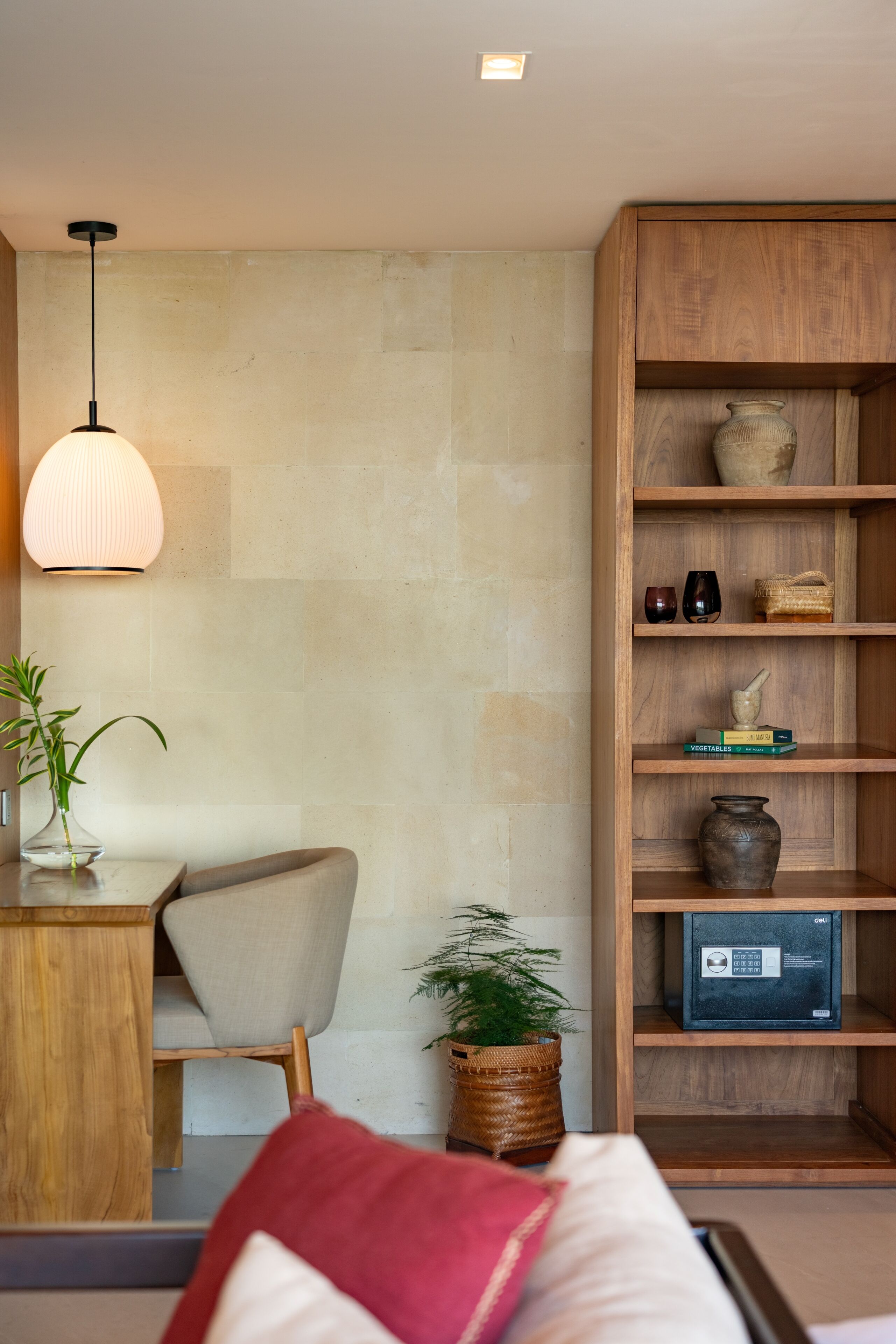 A modern living room with a wooden bookshelf, a dining area with a table and chairs, and a hanging light fixture.