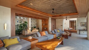 Amplia sala de estar con diseño moderno, que incluye un gran sofá, mesas de centro de madera y un techo con un diseño único.