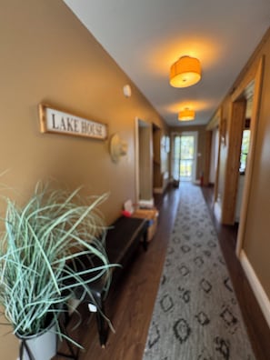 A hallway with a sign reading 'LAKE HOUSE,' a potted plant, and patterned carpet. - Lake Superior Lake House | King Primary with ensuite & private balcony (Goulais River)