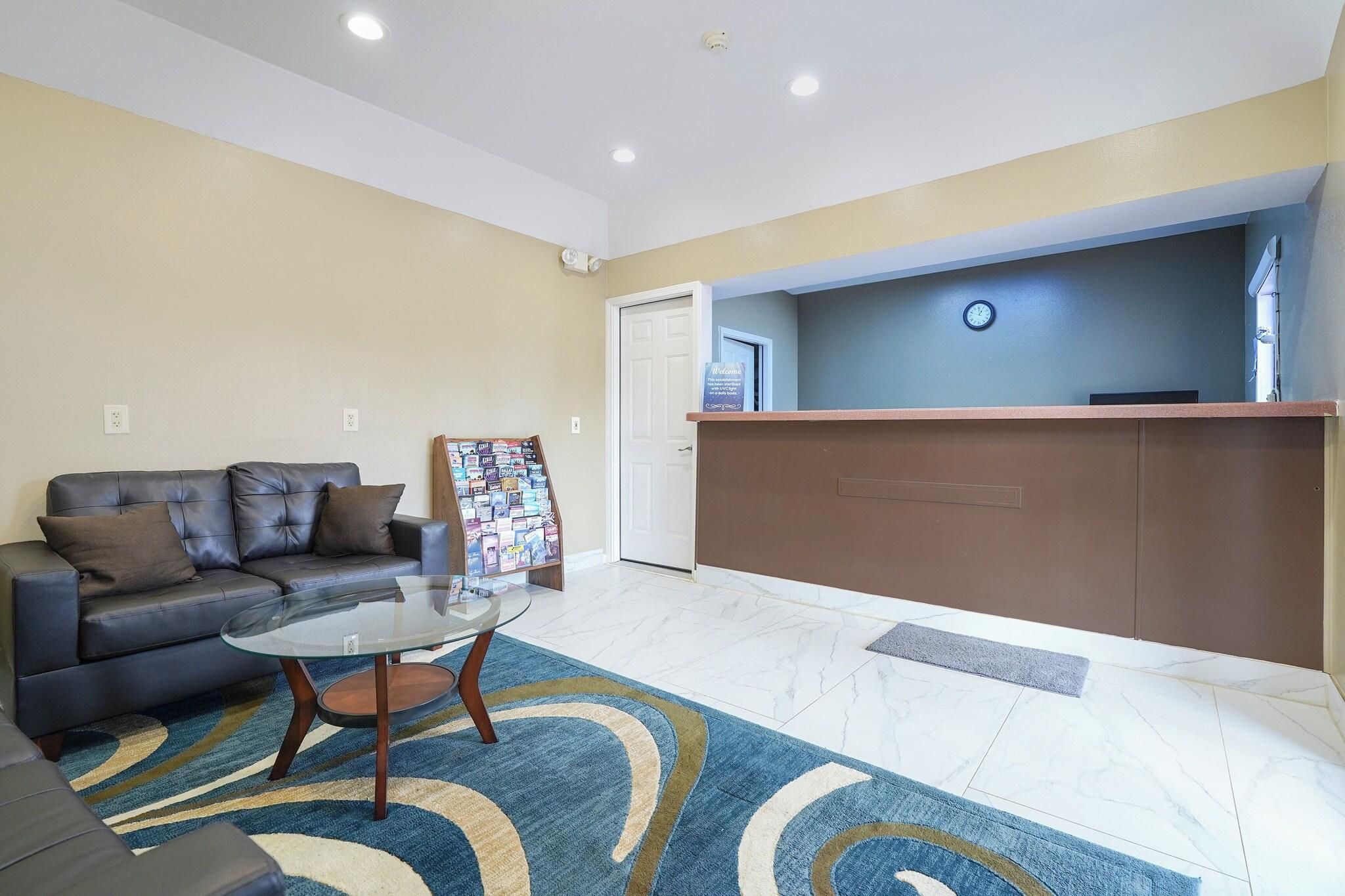 A reception area with a reception desk, a sofa, a glass-top table, and a patterned rug.