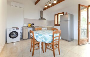 Eine kompakte Küche mit Waschmaschine, Kühlschrank und Esstisch mit Stühlen.