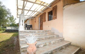 A building with a covered porch, stone steps, and a potted plant.