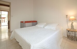Ein Schlafzimmer mit Bett, Nachttischlampe und Blick ins Freie.