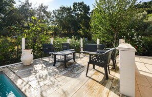 Eine Terrassenanlage im Freien mit Pool, Sitzgelegenheiten und einer weißen Säule.