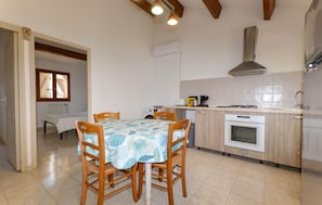 A compact kitchen with a dining area, featuring a table with chairs, a stove, and a sink.