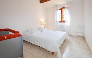 A bedroom with a bed, a chair, a lamp, and a window with curtains.