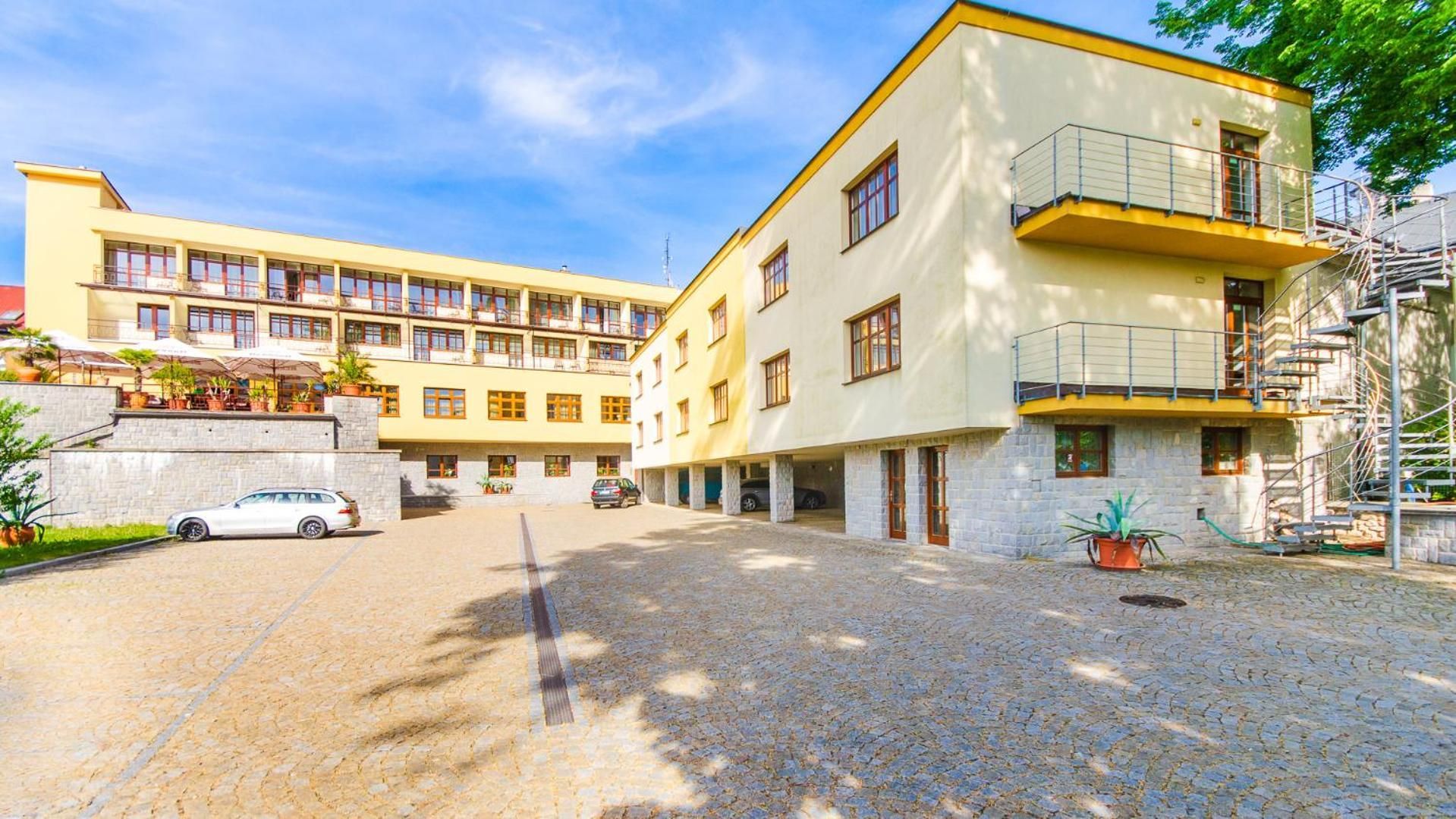 Un hotel de varios pisos con un patio interior, asientos exteriores y una zona de estacionamiento.