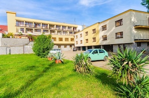 A residential building with multiple balconies and a parking area.