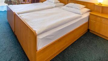A double bed with wooden headboard and footboard, two bedside tables with lamps, a chair, a small table with fruit, and a framed picture on the wall.