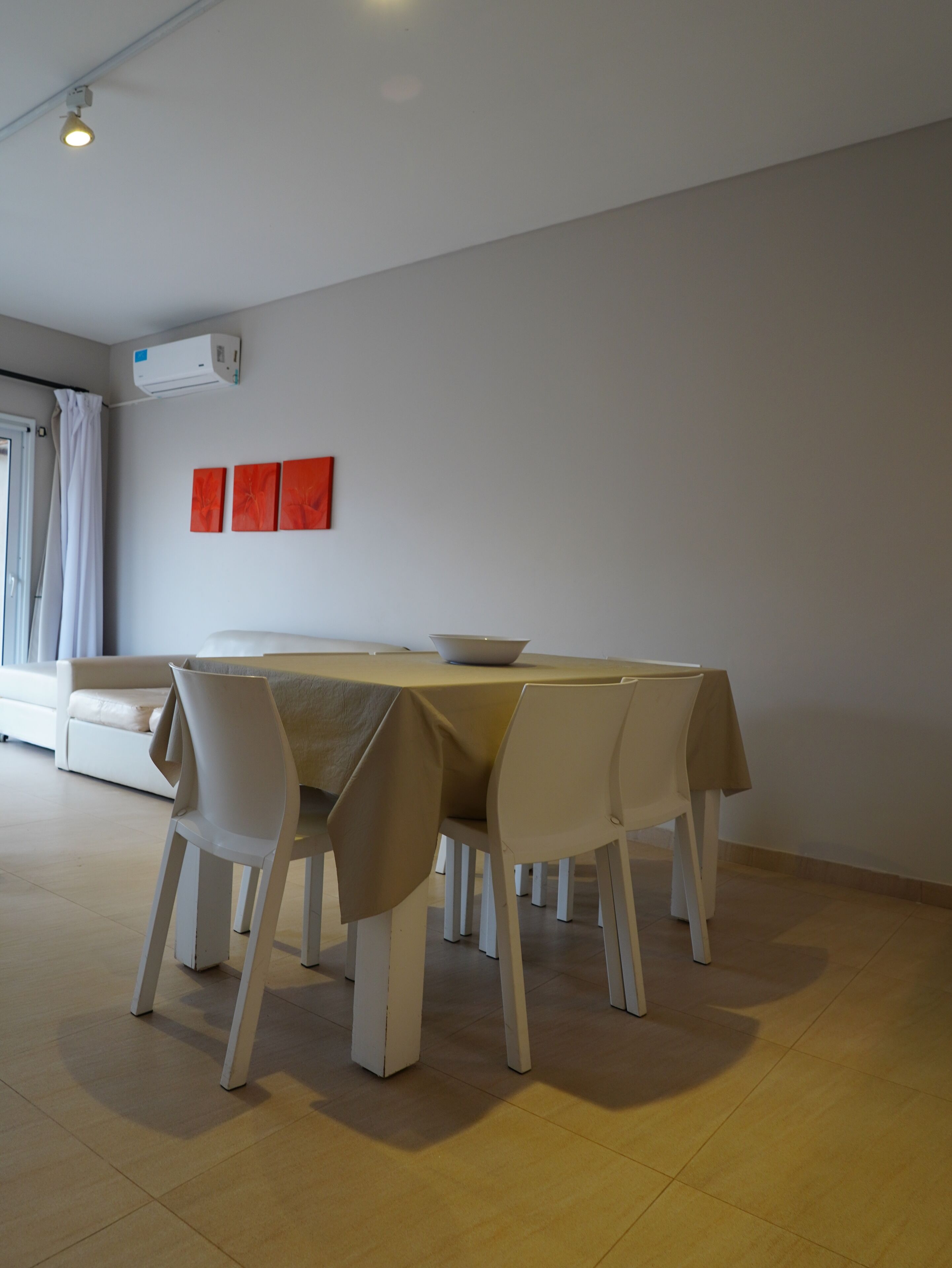 Un comedor con una mesa y sillas, un sofá y una ventana con cortinas.