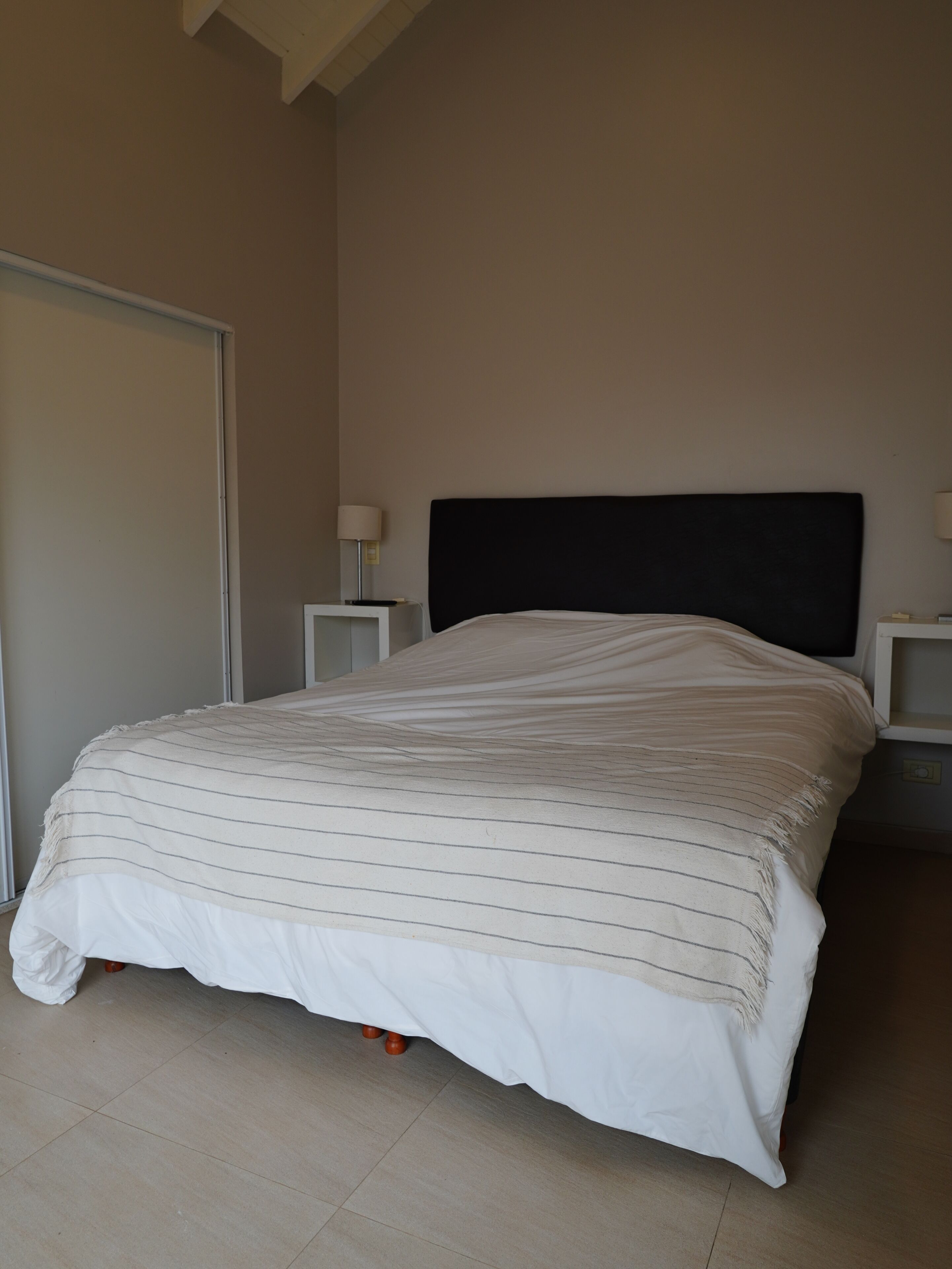 Une chambre à coucher avec un lit, deux tables de chevet et une petite table d’appoint.