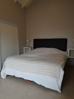 A bedroom with a bed, two bedside tables, and a nightstand.