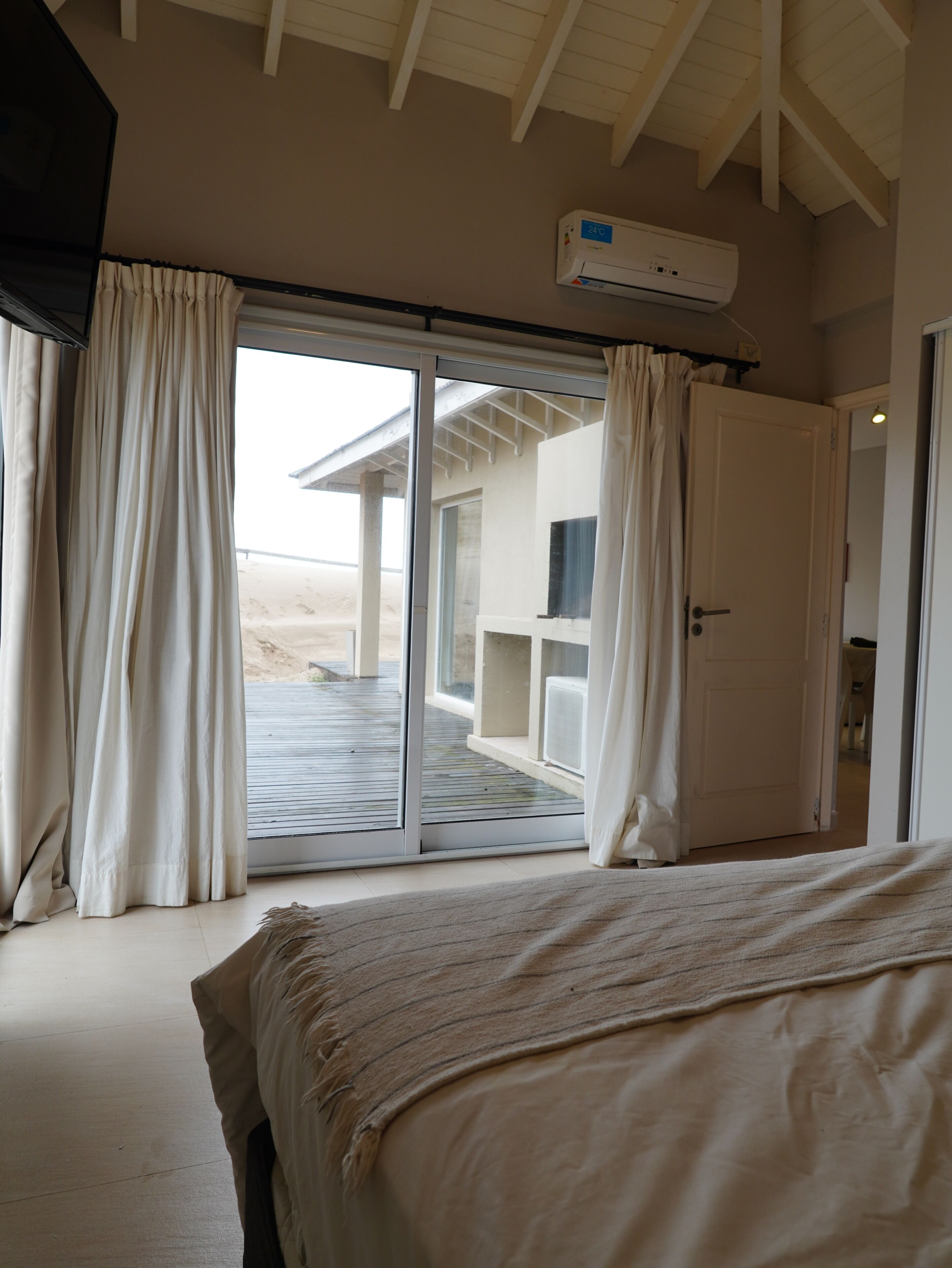 Un dormitorio con una cama, un ventanal corredizo que da a un área exterior y un ventilador de techo.