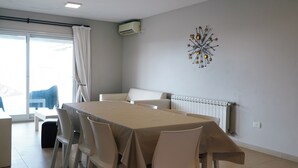 Un comedor moderno con una mesa rectangular, sillas blancas, una lámpara en el techo y un elemento decorativo en la pared.