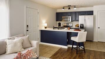 Une cuisine moderne avec des meubles de couleur sombre, un îlot central et un tabouret de bar.