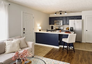 A modern kitchen with dark cabinets, a central island, and a bar stool.