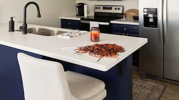 Una cocina moderna con una isla central, armarios azul oscuro, electrodomésticos de acero inoxidable y una silla blanca.