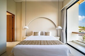 Habitación de hotel moderna con una cama grande, dos lámparas de noche, vistas al exterior y una puerta de madera.