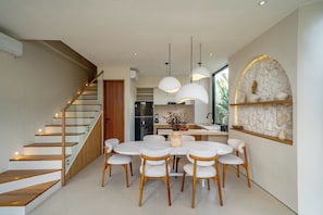 Eine moderne Küche mit Kochinsel, Holztreppe und Pendelleuchten.