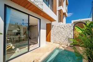 Ein modernes Haus mit Glasfassade, einer Steinwand, einem Pool und einer Treppe zum Innenbereich.