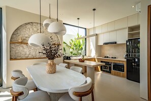 Une cuisine moderne avec un mur d’accent en pierre, une table à manger avec des chaises et une grande fenêtre.