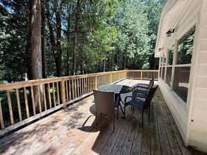 A wooden deck with a table and chairs, surrounded by trees.