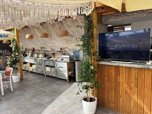Een modern café met een marmeren toonbank, macramé decoraties en een televisie waarop 'Morning Energy' staat.