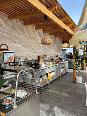 A buffet area with marble countertops, a wooden ceiling, and a wall with a marble pattern. - Hotel Ilio (Ksamil)