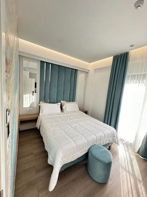 Ein modernes Schlafzimmer mit einem großen Bett, einer Bank und einem blauen Hocker.