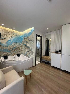 Un baño moderno con una bañera independiente, piso de madera y un amplio mural abstracto en la pared.