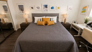 Ein ordentlich eingerichtetes Schlafzimmer mit einem großen Bett, Nachttischen, einem Schreibtisch und einem Stuhl.