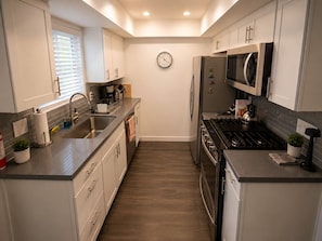 A modern kitchen with a stainless steel sink, a microwave, and a stove. - Modern  1-bedroom condo with AC in sunny Palm Springs (Palm Springs)