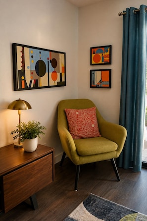 A room with a green armchair, a small table with a lamp and plant, and abstract art on the wall. - Modern  1-bedroom condo with AC in sunny Palm Springs (Palm Springs)