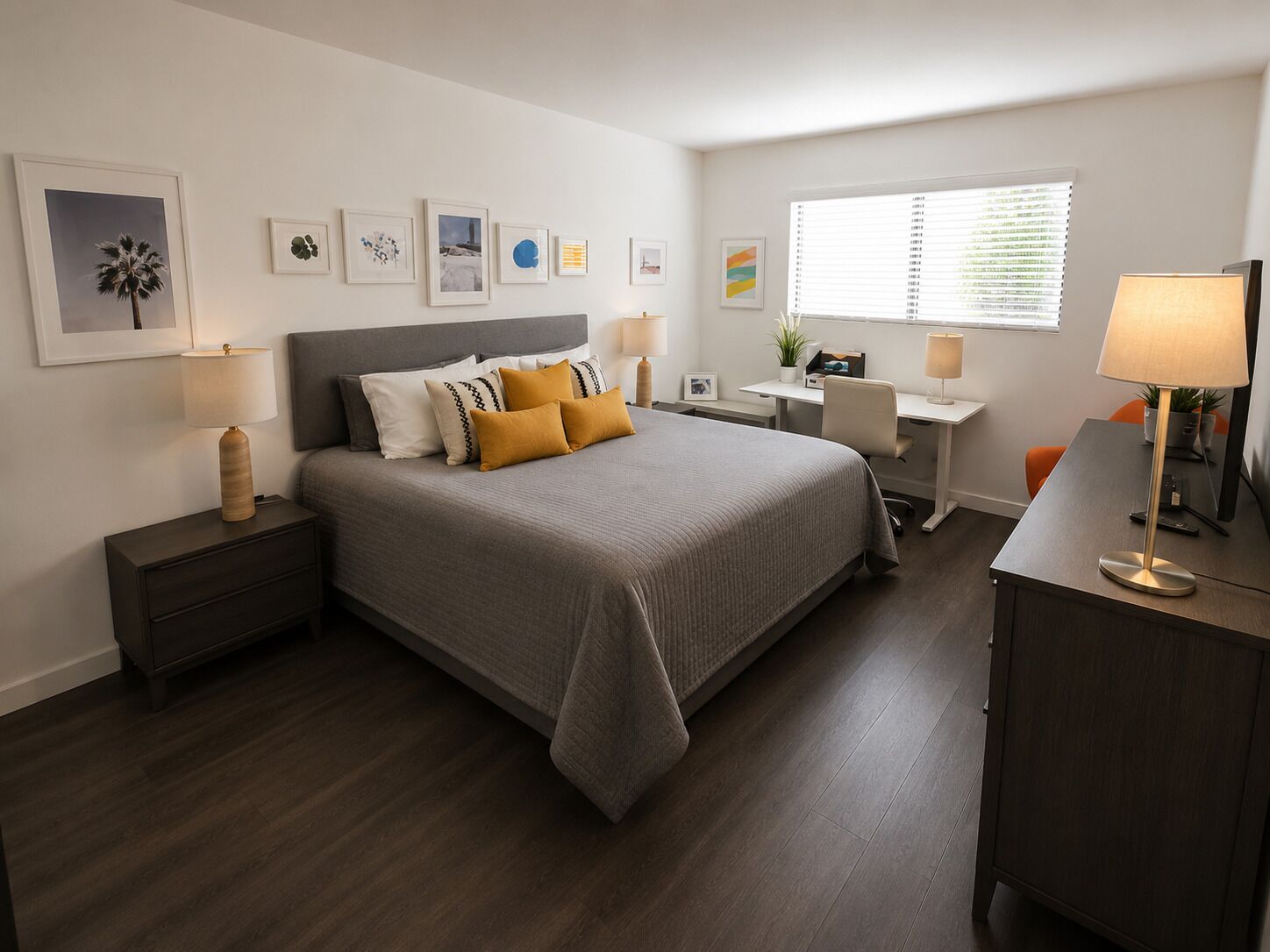 Un dormitorio moderno con cama, mesitas de noche, escritorio y una silla.