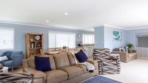 A living room with a sofa, armchairs, and a dining area with a table and chairs. - Rennies Sands | A Surfer's Dream by Rennies Beach (Ulladulla)