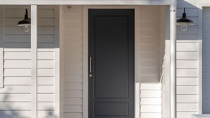 A house with a dark front door, white siding, and two black exterior lights. - Molly-a-la-Plage - Beautiful, spacious and modern beach house in Mollymook Beach (Mollymook Beach)