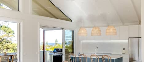 A modern kitchen with a large island, pendant lights, and a view of the outdoors.