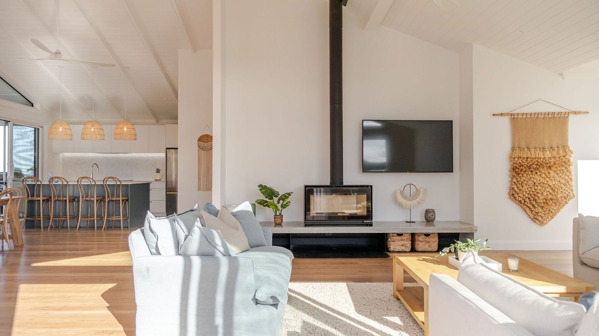 A modern living room with a sofa, coffee table, and a flat-screen TV mounted on the wall.